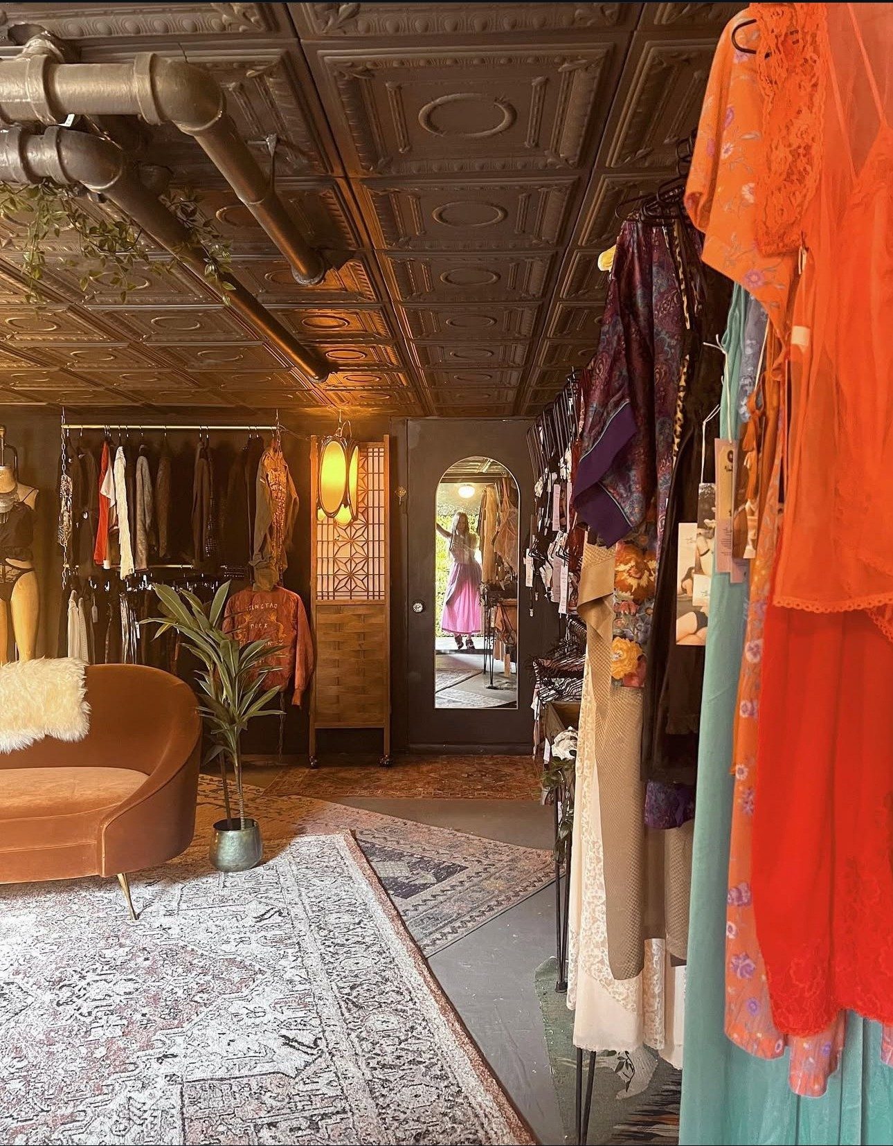 Inside the Hidden Gem shop in Hudson: pressed-tin ceiling, layered rugs, a pink velvet chair and rails of vintage clothing leading to the back door
